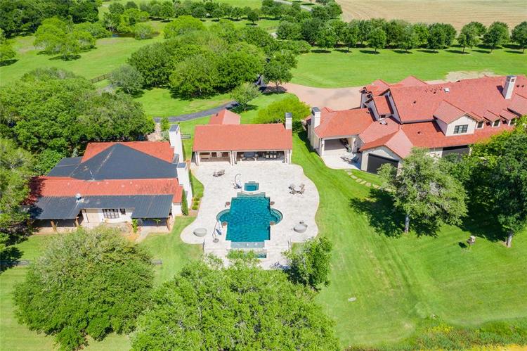 View of the guest and main houses situated on both sides of the complex's heated/over-sized pool with infinity edge/water features/hot tub, fire pit and covered outdoor kitchen and dining areas - all surrounded by  open pasture areas with native Pecan/Mixed Oak/Mesquite trees!