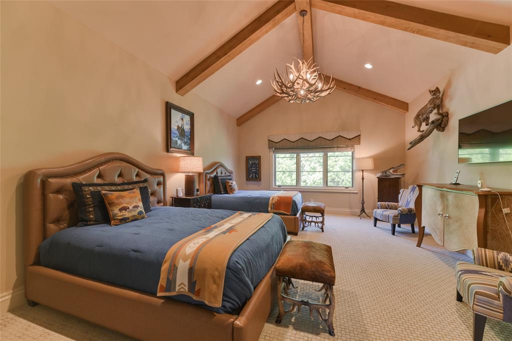 The second of three upstairs GUEST BEDROOMS (20 X 16) includes carpeted flooring, pitched ceiling with exposed wood beam/antler hanging chandelier/recessed lighting, mullioned windows with decorative Roman shades/valence, two walk-in closets (shelving/hanging compartments) and en suite bath.