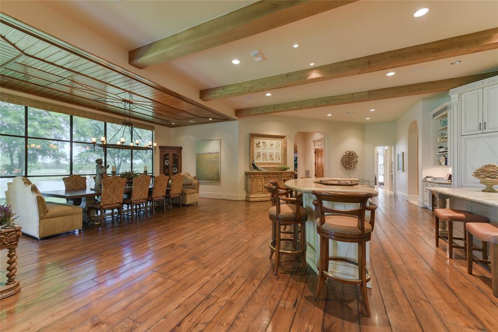 The well-planned DINING AREA with nearby KITCHEN and its two CENTER ISLANDS with SEATING - so created to encourage family and friends to gather casually amidst a spacious area with several seating arrangements. The DINING AREA (22 X 15) includes hardwood flooring, decorative wood planked ceiling/hanging light fixture, floor to ceiling windows overlooking outdoor landscape.  The KITCHEN (27 X 28)  includes two center islands with bar seating (stone counters, stained wood cabinets).