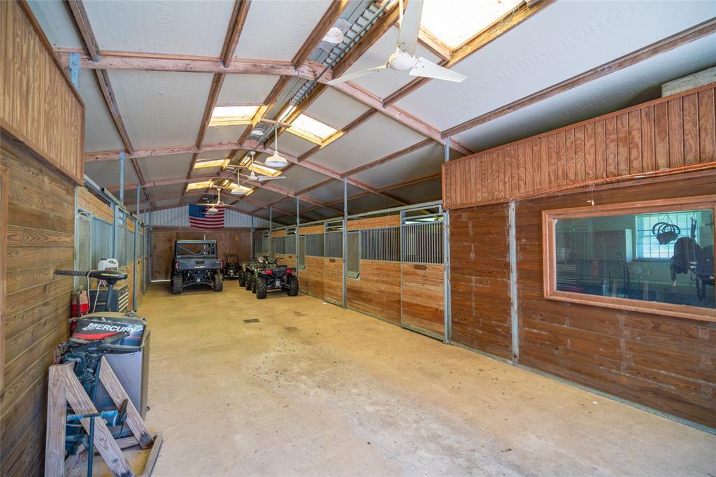 Interior of the HORSE BARN with its low pitched ceiling with fans/lighting fixtures, wood/metal stall doors and windowed office room.