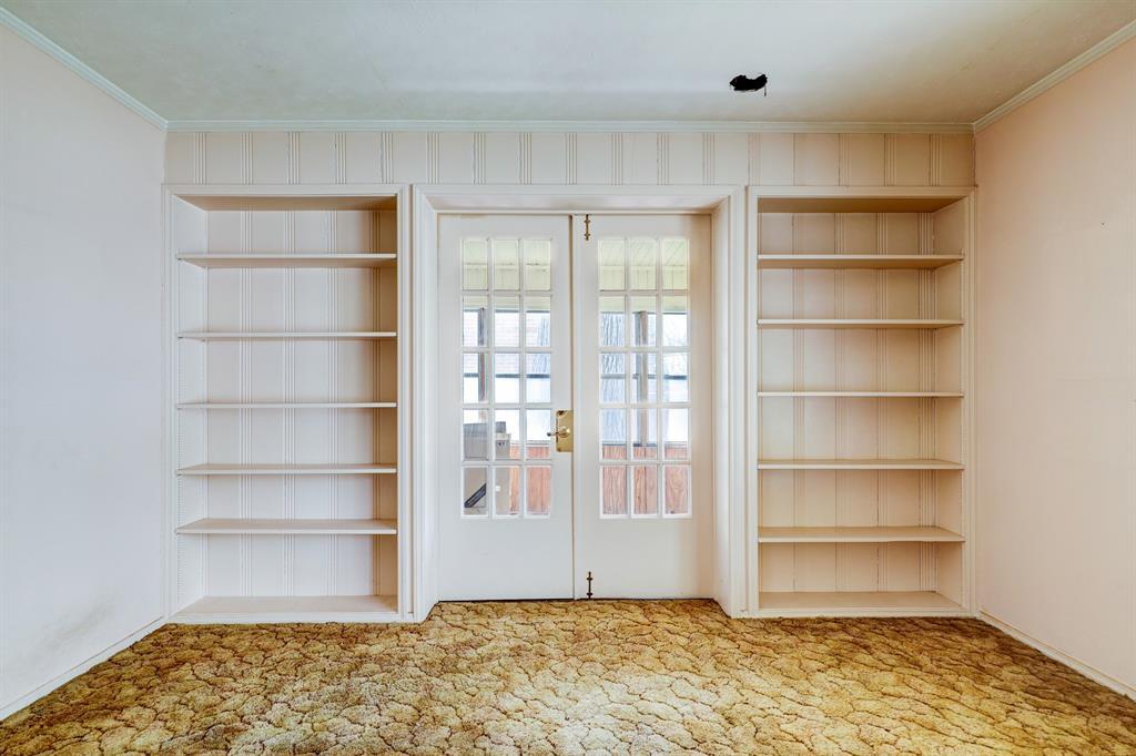 The family room has built-in shelving on each side of French doors leading to an enclosed porch.