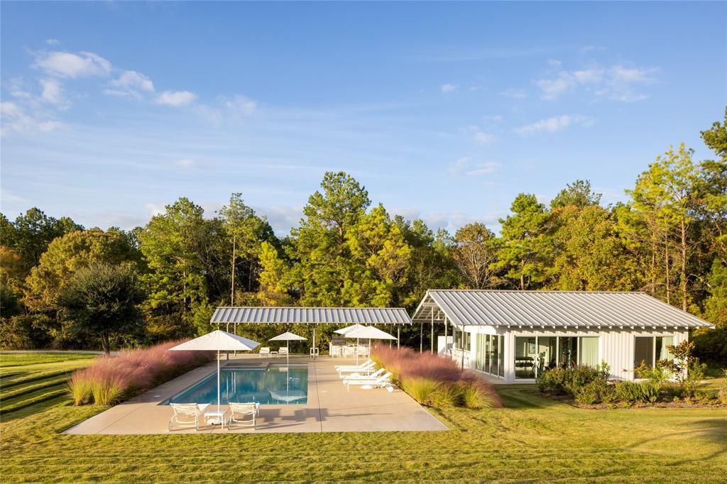 The pool house is surrounded by the plush landscape and thick woods