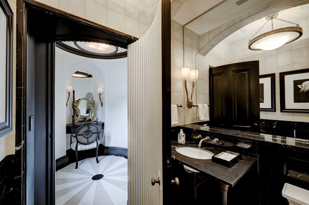 Formal Powder Room off foyer with limeston and marble medallion floor, fluted wood walls and a private water closet.