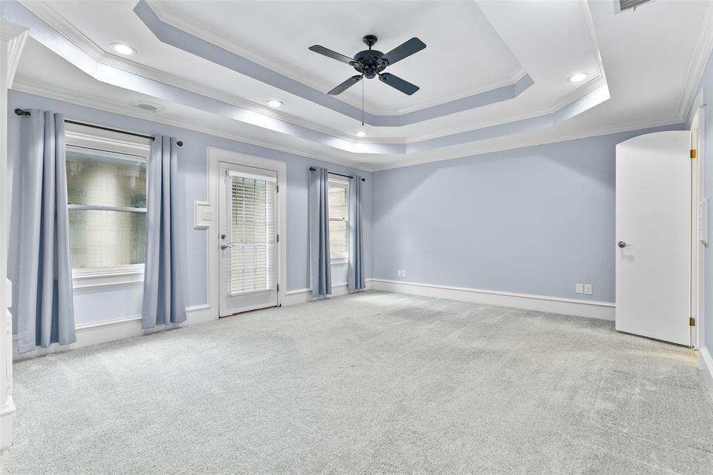 Escape to the privacy of the master suite that boasts a double trayed ceiling with a ceiling fan, recessed lights, custom paint, oversized baseboards, recently replaced carpet, a private patio exit, and a wall of custom built-in cabinetry and shelving.