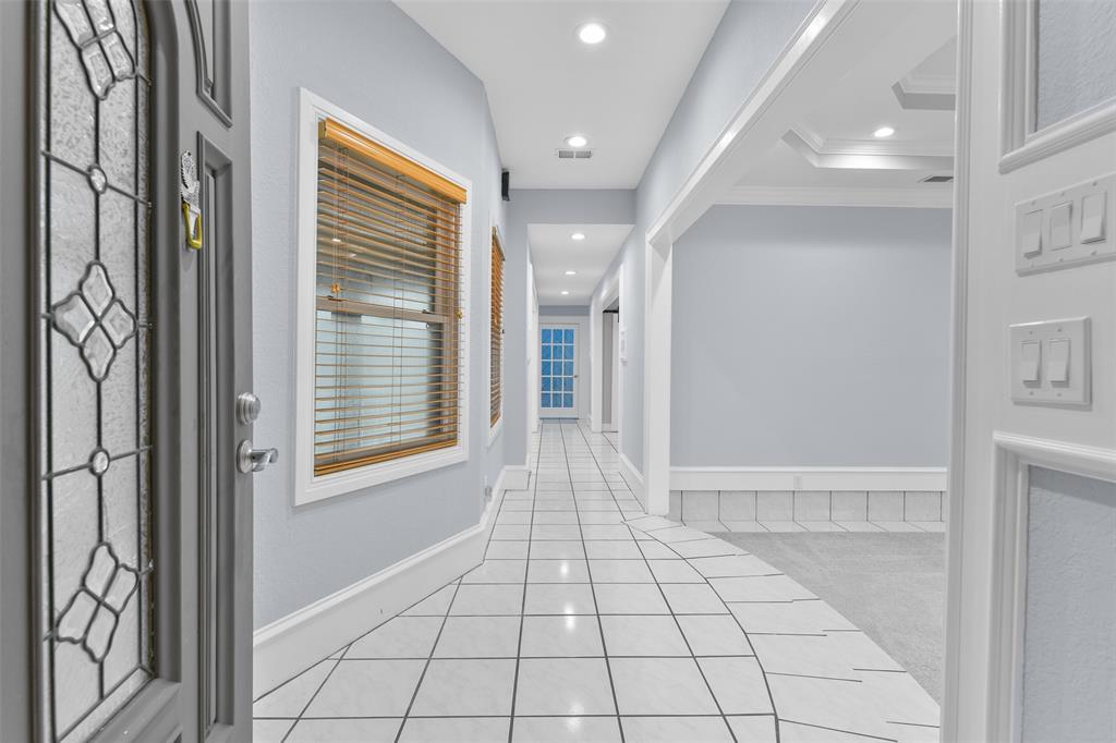 A painted wood front door with leaded glass detailing opens from the gated courtyard into an inviting foyer where you'll notice recent interior paint with oversized 9-inch baseboards, recessed lighting, and easy maintenance tile flooring.