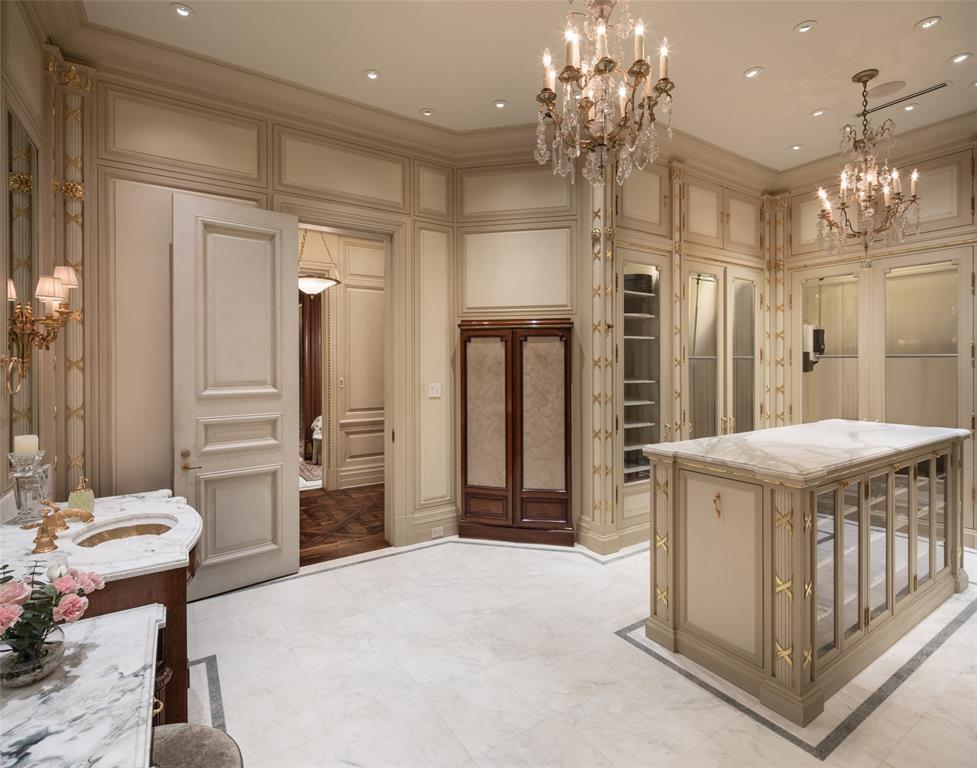 The first boutique-inspired Primary Suite walk-in closet tames even the most extensive wardrobe with rows of glass-faced mahogany cabinetry, marble vanity and packing islands, endlessly customizable components, white inlaid marble floors and ornate lighting.