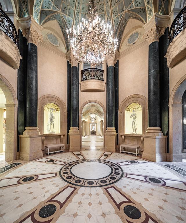 Five different types of marble comprise the inlaid floor of the Rotunda. Iron scrollwork Juliet balconies rise above illuminated scallop-trimmed art niches and bench seating.