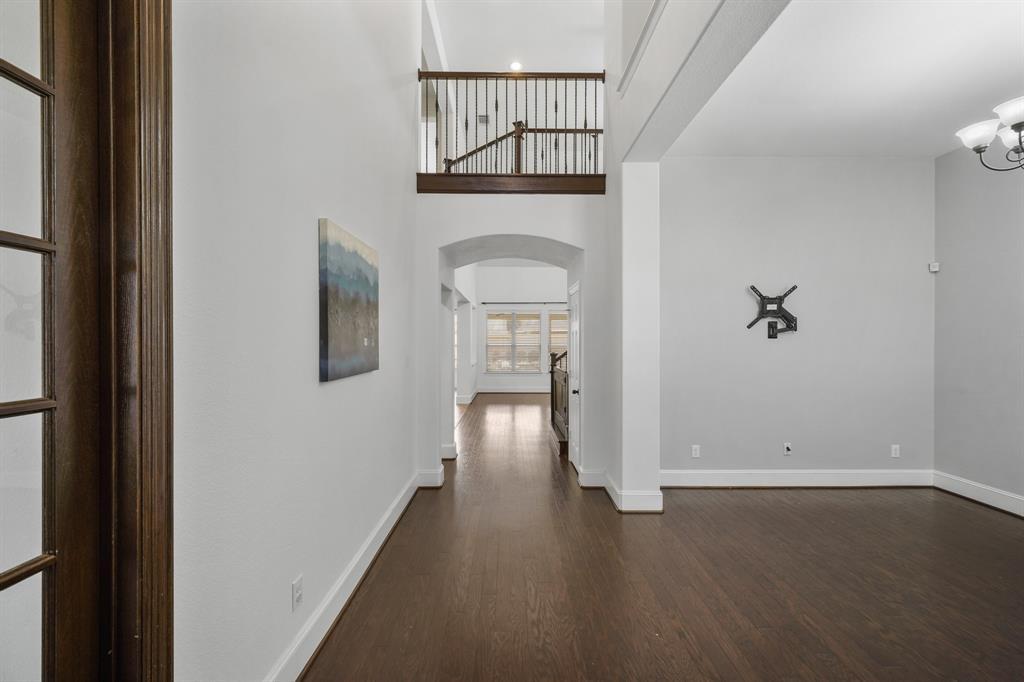The foyer of the home with a soaring ceiling and wrought iron balcony views from above features pendant chandelier lighting, a coat storage closet with under-stair storage & hardwood floors. The air conditioning system's coils were rebuilt in 2023.