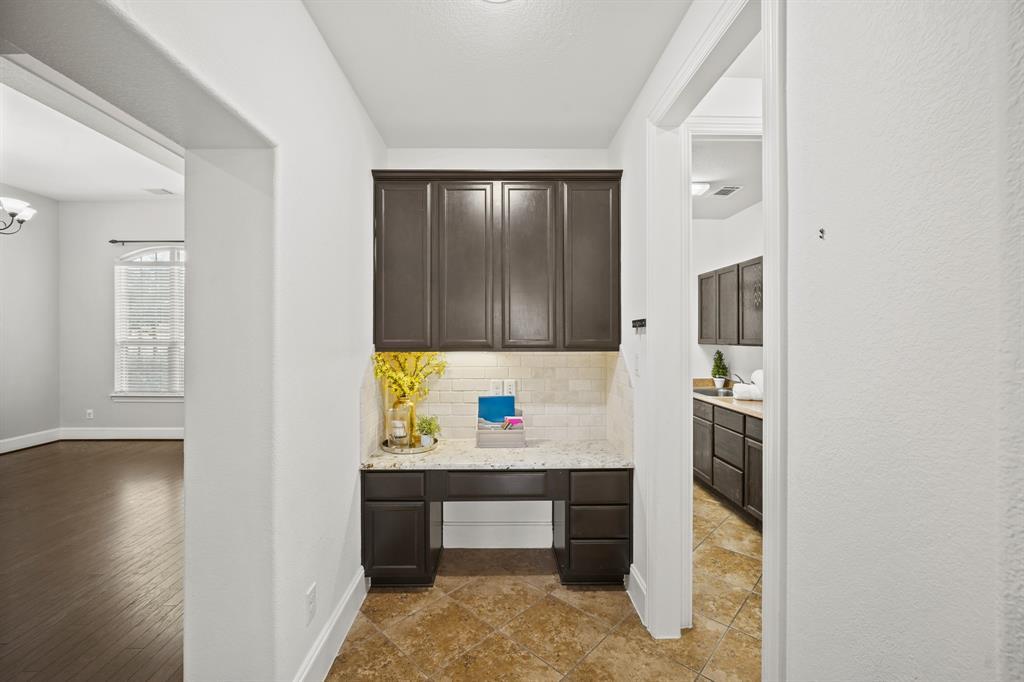 Just off the kitchen is a corridor leading to a second bedroom down, full bath & utility room. Included is a built-in desk area with upper wood-stained cabinetry, a granite surfaced desk with tiled back splash & under-cabinet lighting and diagonally-laid tile flooring.