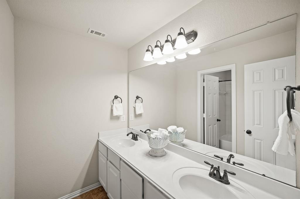 Located just outside the fourth & fifth bedrooms is the home's fourth full bath with painted cabinetry, dual sinks, wall mounted mirror & lighting and a private water closet complete with a tile surrounded combination tub/shower & tile flooring.