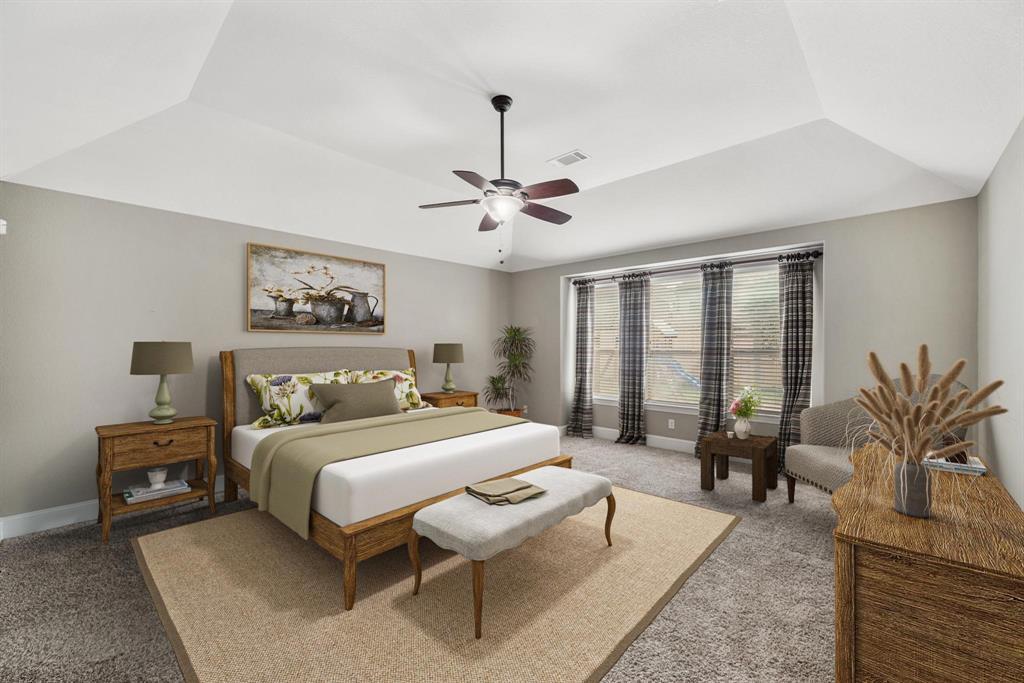 Located on the back of the home, the owner's suite with high ceiling and ceiling fan with lighting includes windows with blinds overlooking the backyard & carpet. This photo has been virtually staged.