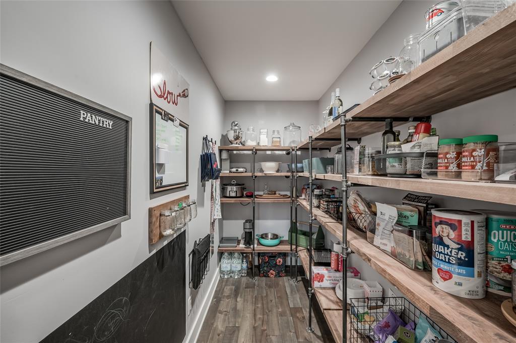 Fabulous walk-in pantry with wood and iron shelves and recessed lighting.