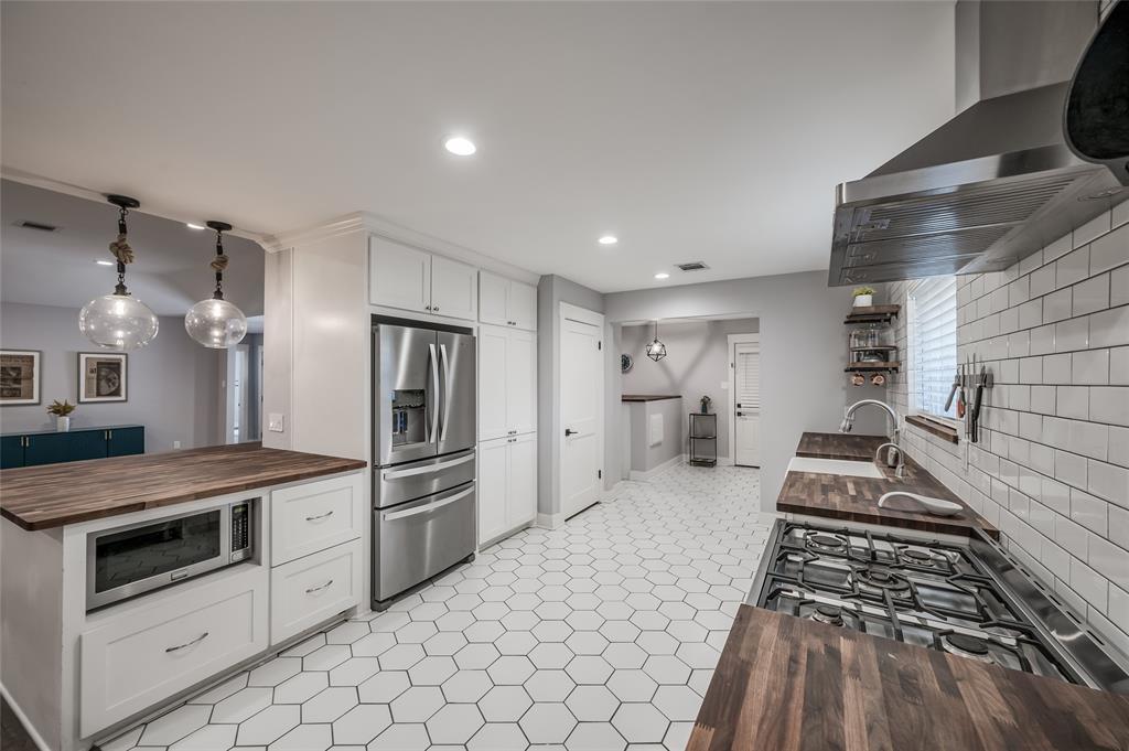 Renovated kitchen is a cooks delight and features custom wood countertops w/white subway tile backsplash, updated stainless appliances, food prep area, and huge walk-in pantry.