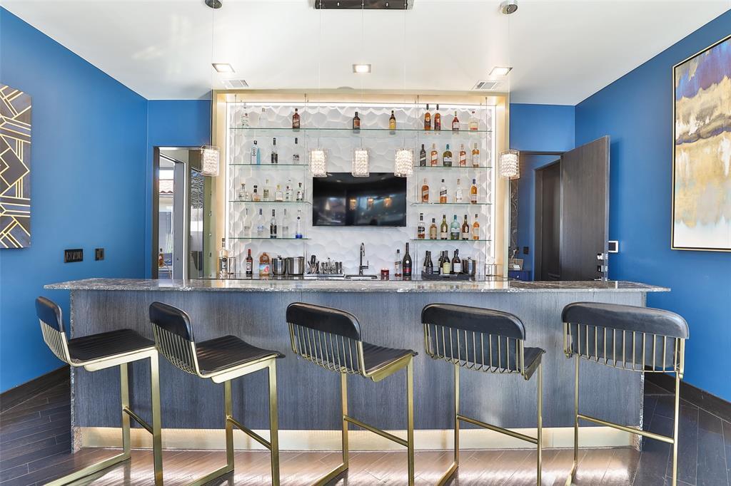 This custom bar can rival any of the best aesthetic bars in Houston with custom cabinetry, glass shelving, robust counters and a textured modern wall accent feature.