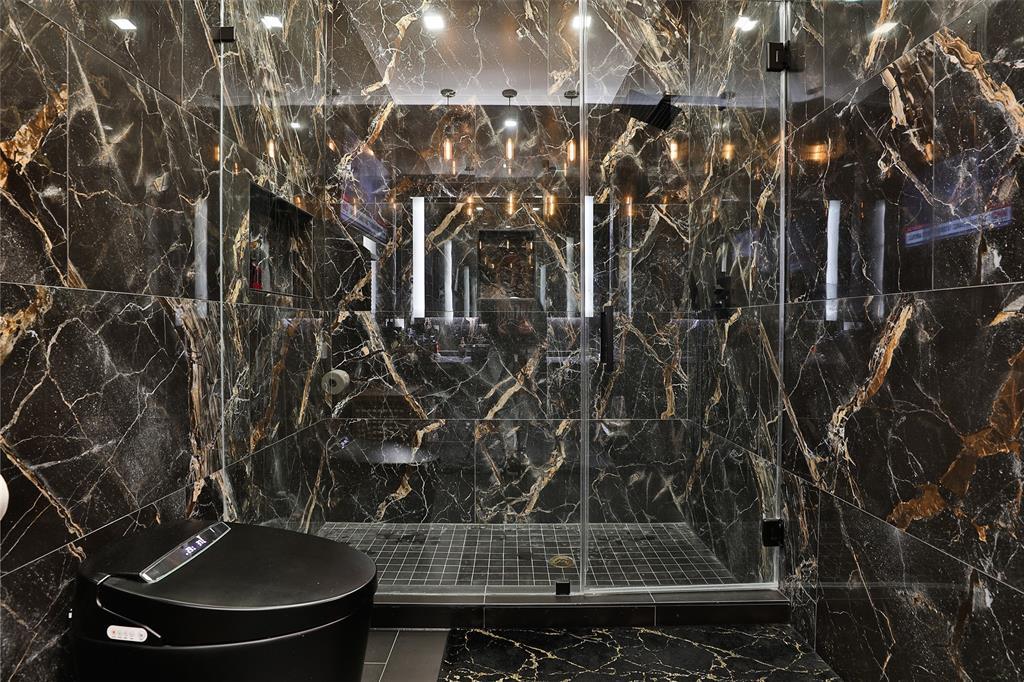 The spa like seamless glass shower is shrouded in understated Ellesmere tile masculinity. Not shown is "His" custom closet, out of a men's custom suit tailor atelier.