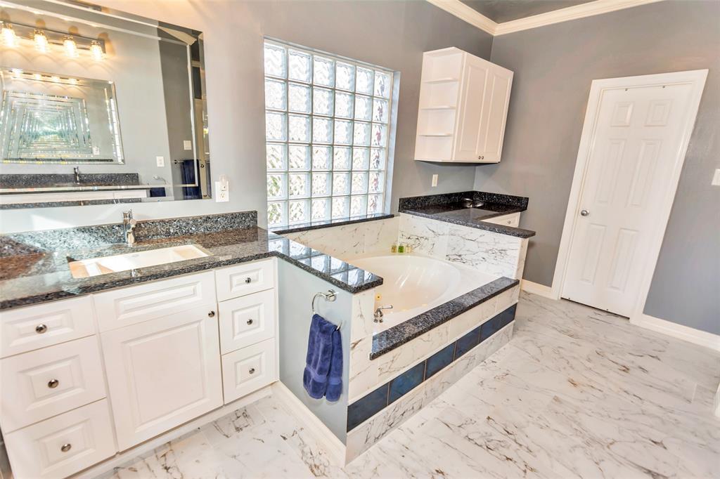 Bathroom offers dual his and her vanities with lots of storage, granite counters, beveled glass mirrors and updated light fixtures.