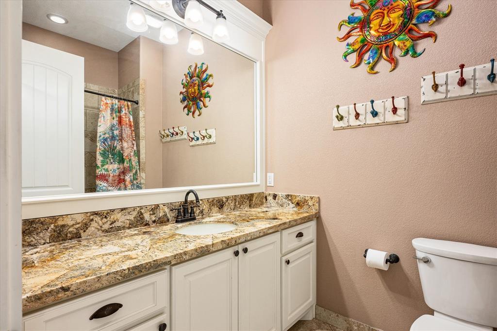 This hall bath, nicely accommodates guests with granite vanity, stone tile floor and tub surrround.