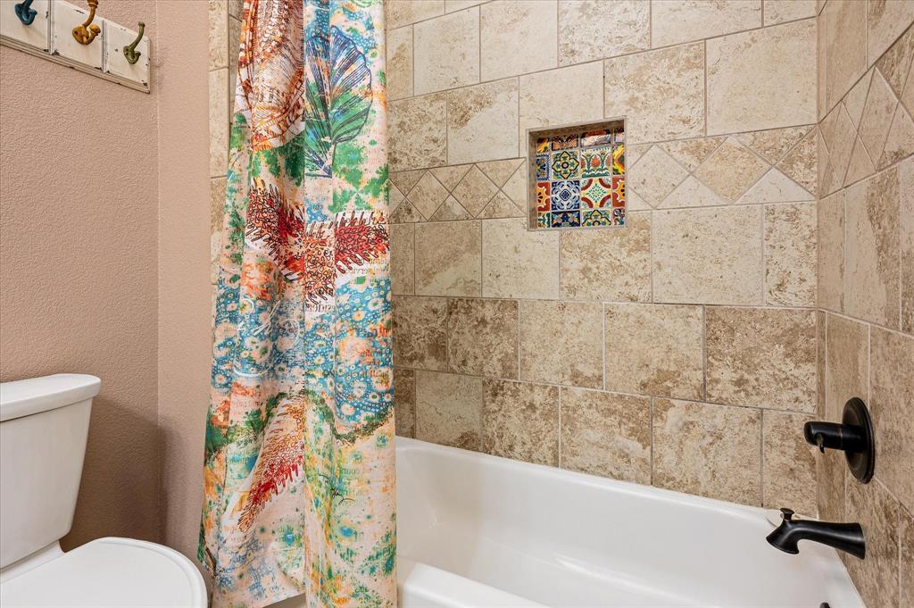 Colorful decorative tile cheerfully accents the travertine tile tub/shower surround.