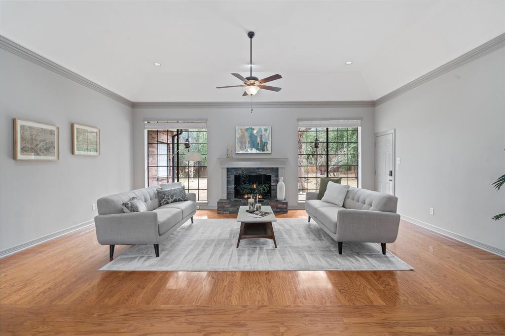 The spacious living room features beautiful hardwood floors and a gas log fireplace. Large windows provide a stunning view of the backyard and the surrounding greenery.