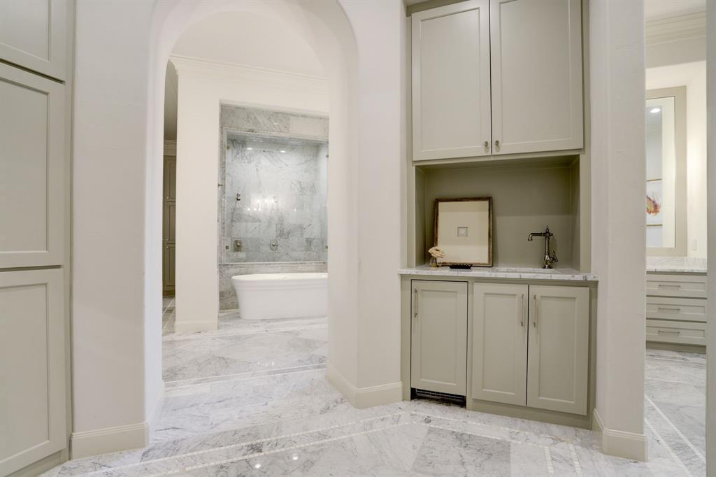 Enter the primary en-suite bath thru a foyer that contains a coffee bar with ice maker and additional storage.