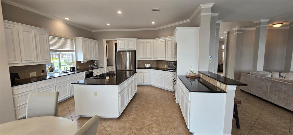 Kitchen open to living and has a gas cooktop on the island, breakfast area and overlooks the sparkling pool