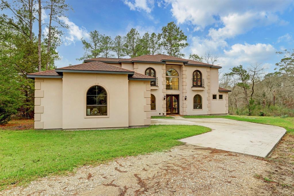 The home’s impressive facade commands attention with its stucco finish, grand arched windows, and a regal entryway. The expansive driveway leads to a home of distinction, promising a luxurious living experience set against a backdrop of natural beauty.