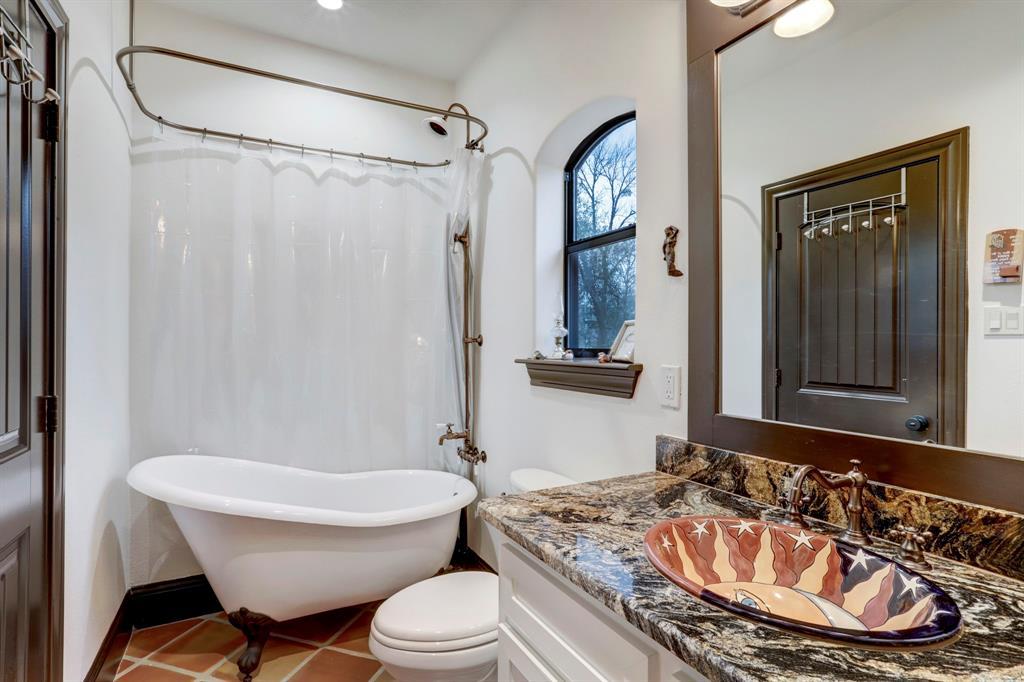 Step into a space where vintage charm meets modern living. This unique bathroom showcases a classic clawfoot tub, perfect for soaking away the day's stress. A stylish granite vanity with a custom basin, terracotta flooring, and a quaint window create a cozy and inviting environment.