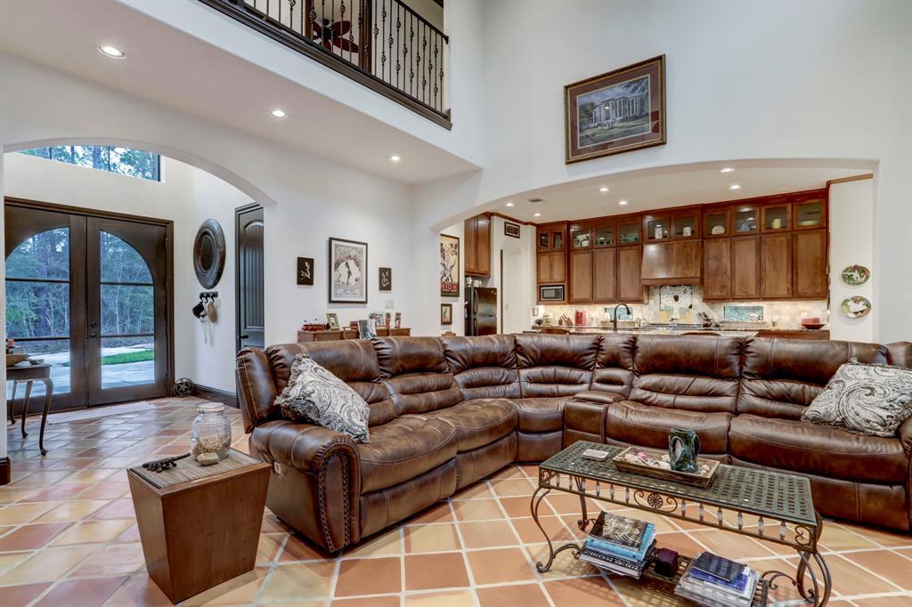 The heart of the home, this living room is a blend of comfort and elegance with its high ceilings, large arched doorways, and a seamless flow into the kitchen area. The large sectional sofa invites family gatherings, while the terracotta tiles add warmth and rustic charm.