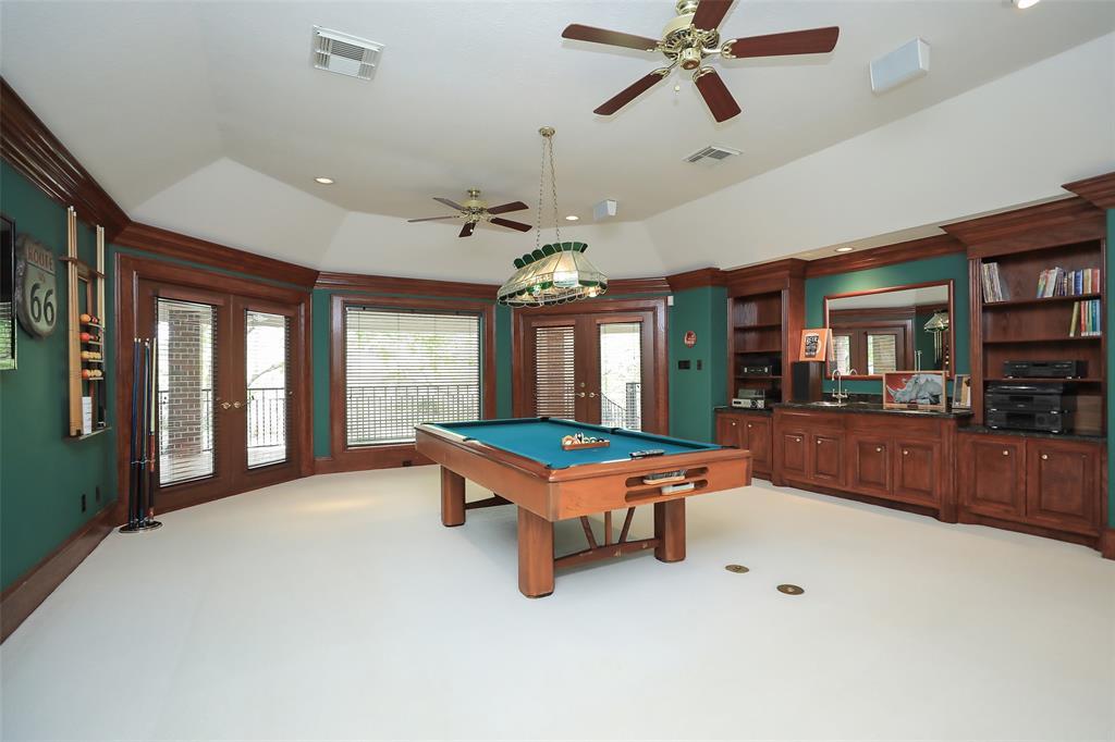 The game room is a great size and features a wall of convenient built ins and access to the balcony overlooking the pool