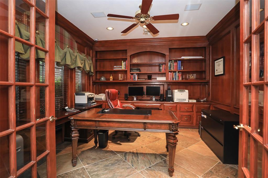 The study is well appointed with a built-in desk and enveloped in rich and warm wood paneling.