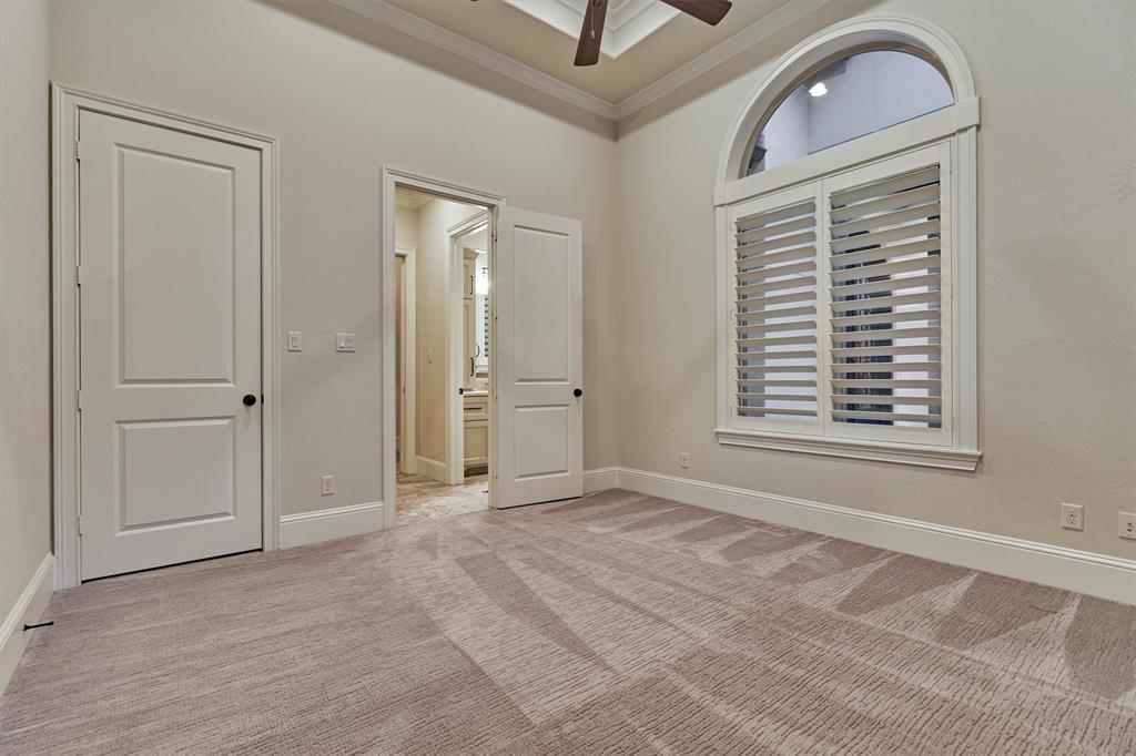 Secondary bedroom with tray ceiling, plush carpeting and plantation shutters.
