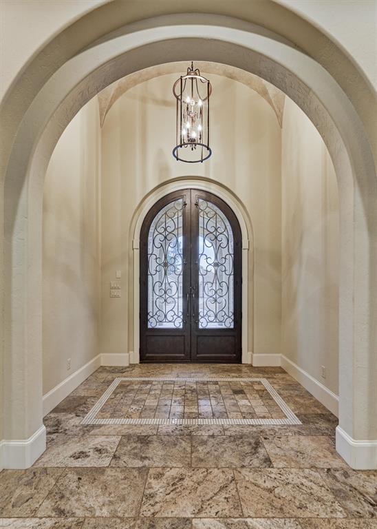 The old-world charm continues in the arched foyer showcasing the intricate wrought iron double door entrance.