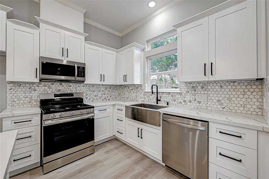 First-floor living with luxurious finishes including quartz worktops, stainless steel appliances, contemporary shaker cabinetry, and hardware throughout the house. Interior photos are from another community by the same builder; finishes and selection may vary.