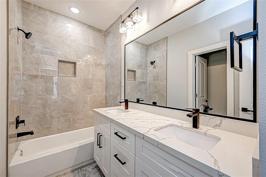 The second bathroom has tile that reaches all the way up to the ceiling. Double-sink vanity. Interior photos are from another community by the same builder; finishes and selection may vary.