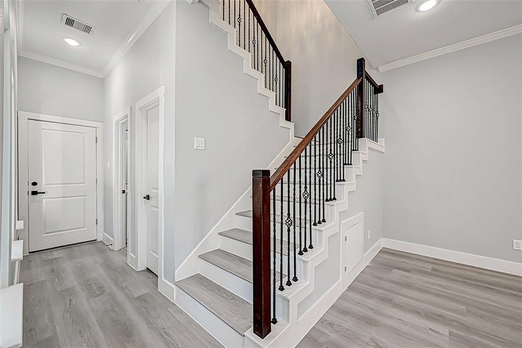 Doors lead into a spacious 2-car garage, a half bathroom, and additional storage space. Iron stair railing. Interior photos are from another community by the same builder; finishes and selection may vary.