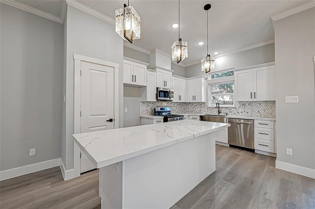 First-floor living with luxurious finishes including quartz worktops, stainless steel appliances, contemporary shaker cabinetry, and hardware throughout the house. Interior photos are from another community by the same builder; finishes and selection may vary.