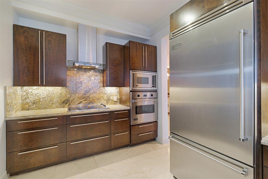 The kitchen features travertine flooring, custom cabinetry, and beautiful granite countertops and backsplash.