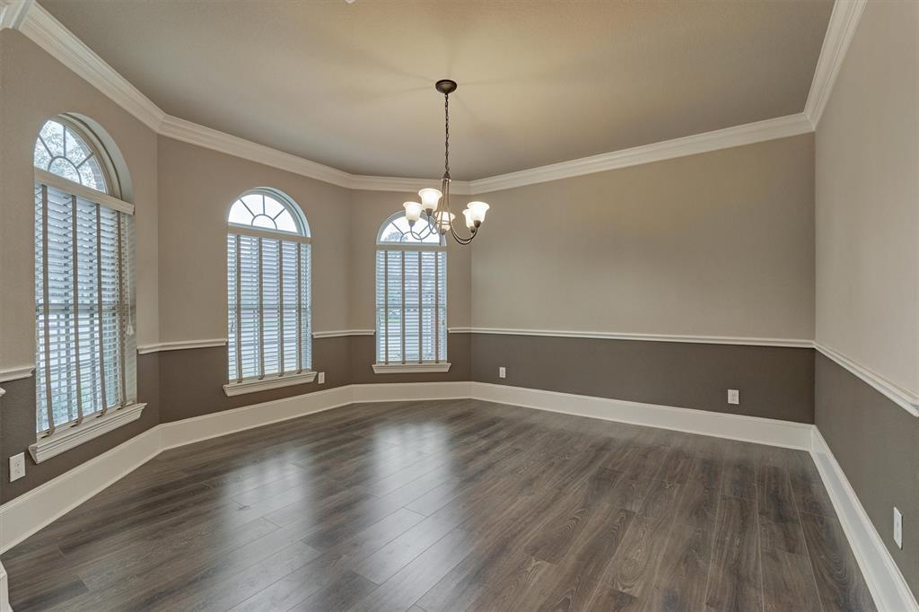This grand dining room with updated wood laminate flooring does not disappoint! Arched windows, custom blinds, and decorative moldings highlight this space.