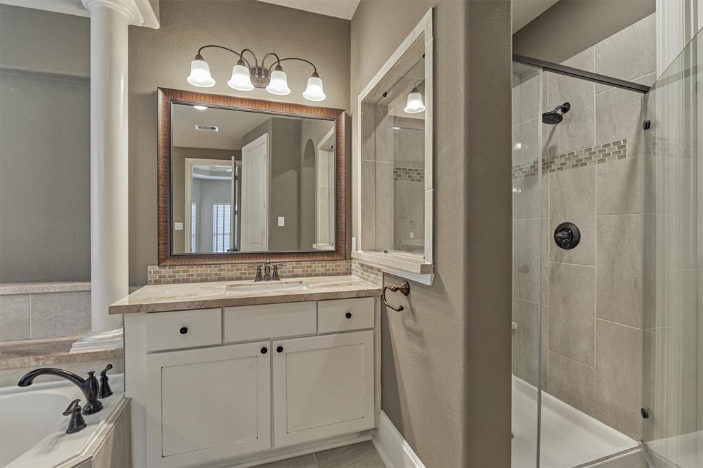 Separate stall shower with bench and attractive tile surround. Well-designed primary bath also features a linen closet.