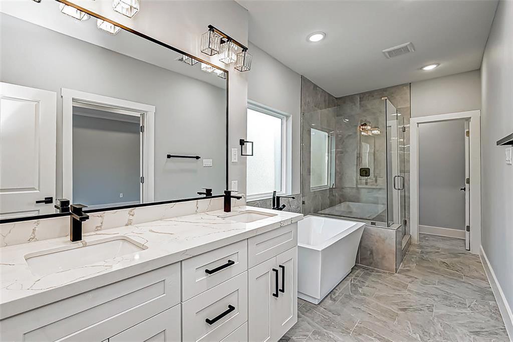 Primary en-suite bathroom with a freestanding soaking tub, separate sizable shower, and an upgraded double vanity. Interior photos are from another community by the same builder; finishes and selection may vary.