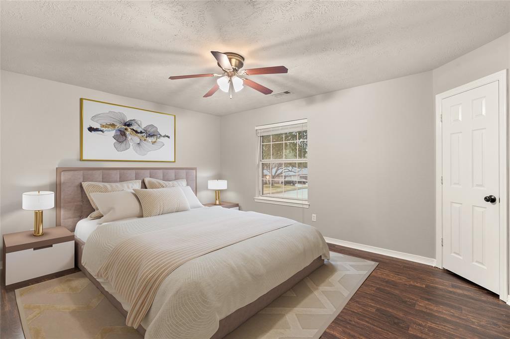 Secondary bedroom features gorgeous flooring, custom paint, dark stained ceiling fan with lighting and a large window with privacy blinds.