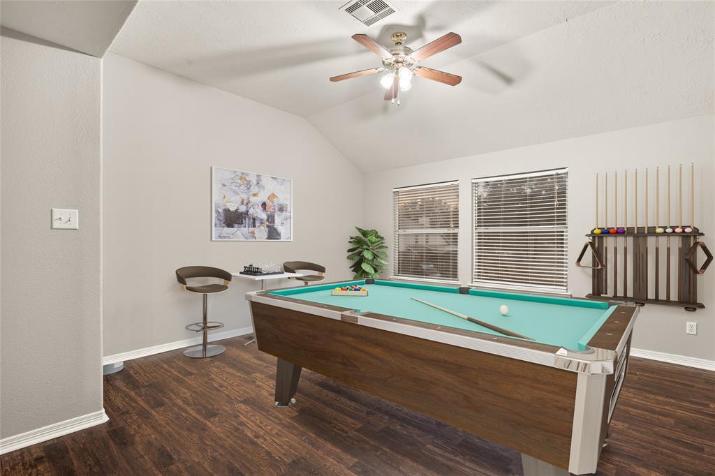 Come upstairs and enjoy a day of leisure in this fabulous game room! This is the perfect hangout spot or adult game room, this space features gorgeous flooring, high vaulted ceiling, custom paint and dark stained ceiling fan.