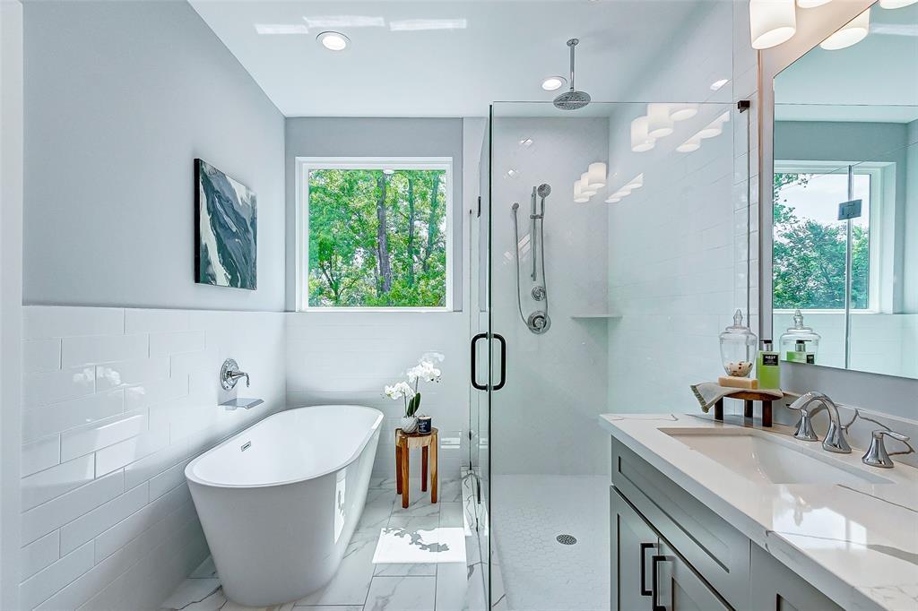 Elegant primary bathroom with a stand alone tub, rainhead and handheld shower. Dual sinks, ample cabinet space and sleek finishes.